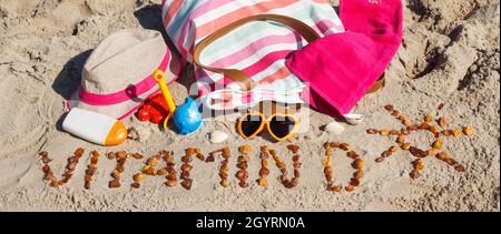 Inscription vitamine D avec forme de soleil, accessoires pour la détente et les enfants jouant sur le sable à la plage. Prévention de la carence en vitamine D. Banque D'Images