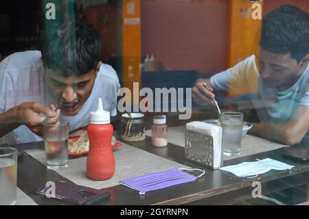 Deux jeunes garçons mangent de la nourriture rapide dans un café intérieur vu à travers le verre de fenêtre Banque D'Images