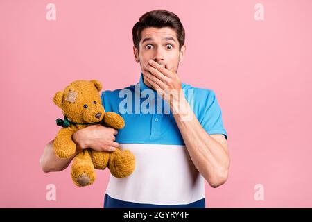 Photo de triste brunet millennium gars tenir jouet porter polo rayé isolé sur fond de couleur rose Banque D'Images