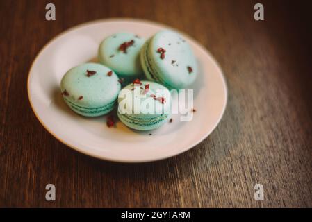 quatre macarons bleu-vert sur la plaque blanche sur la table en bois du café-restaurant Banque D'Images