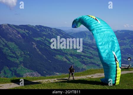 Homme préparant un parapente en descente.Il prend un courant pour lancer son vol dans les montagnes Alp, dans le centre de la Suisse. Banque D'Images