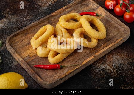 Rondelles de calmar ou oignon dans des ingrédients de chapelure, sur le plateau de service, sur fond de table rustique sombre Banque D'Images