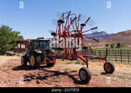 Un râteau rotatif combine de petites rangées de foin en une plus grande rangée pour réduire le nombre de passages nécessaires à la mise en balles de la machine. Banque D'Images