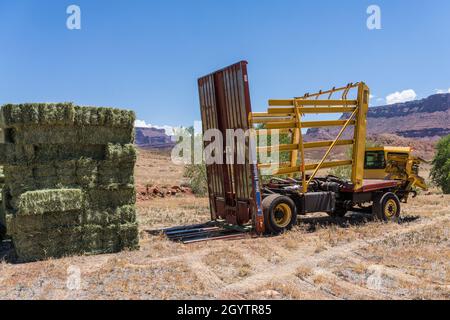 Une remorque autochargeuse ou une remorque autochargeuse se tire vers l'avant après le déchargement d'une pile de balles de foin sur un ranch de l'Utah. Banque D'Images