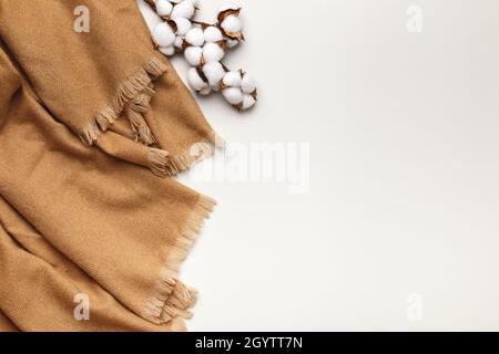 Foulard beige en cachemire avec branche de coton sur fond gris clair.Flat lay, vue de dessus, espace de copie Banque D'Images