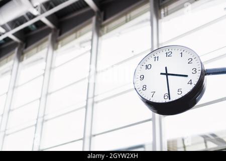 L'horloge en forme de flèche dans le terminal de l'aéroport sur l'arrière-plan des fenêtres. Banque D'Images