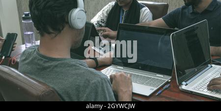 ISLAMABAD, PAKISTAN - 01 septembre 2021 : un groupe d'étudiants assis en plein air à la table qui navigue sur leur ordinateur portable et étudie Banque D'Images