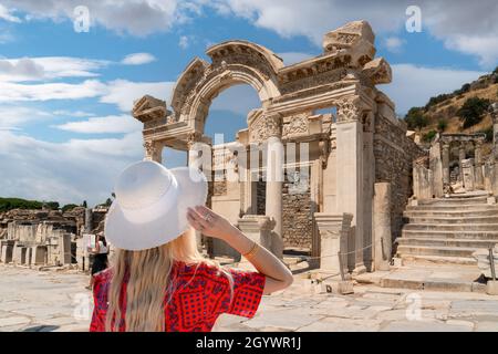 Vue arrière de la fille en robe rouge et chapeau blanc montres Temple d'Hadrien ruines dans la ville antique d'Ephèse, Turquie, un jour ensoleillé d'été, Efes, Izmir, Turk Banque D'Images