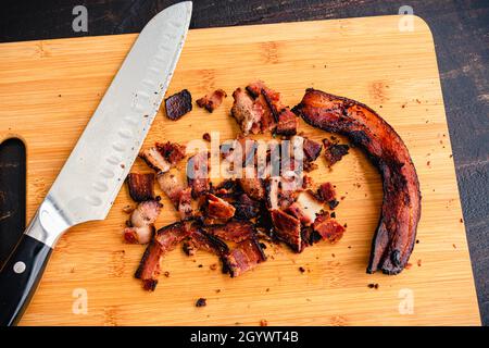 Bacon haché épais sur une planche à découper en bambou : dés de bacon sur une planche à découper en bois Banque D'Images