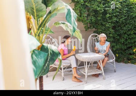Belles femmes âgées se détendant à la maison dans le jardin - deux jolies femmes mûres reposent dans un jardin paisible de cour arrière Banque D'Images