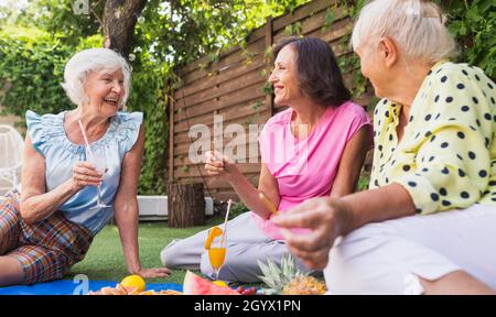 Belles femmes âgées se détendant à la maison dans le jardin - trois jolies femmes mûres reposent dans un jardin paisible de cour arrière Banque D'Images