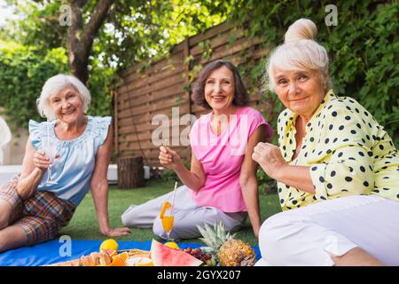 Belles femmes âgées se détendant à la maison dans le jardin - trois jolies femmes mûres reposent dans un jardin paisible de cour arrière Banque D'Images