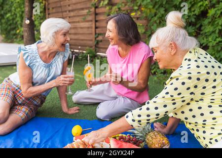 Belles femmes âgées se détendant à la maison dans le jardin - trois jolies femmes mûres reposent dans un jardin paisible de cour arrière Banque D'Images