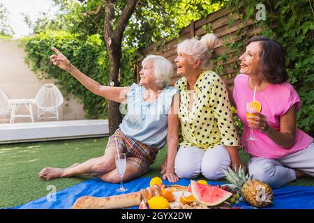 Belles femmes âgées se détendant à la maison dans le jardin - trois jolies femmes mûres reposent dans un jardin paisible de cour arrière Banque D'Images