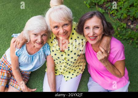 Belles femmes âgées se détendant à la maison dans le jardin - trois jolies femmes mûres reposent dans un jardin paisible de cour arrière Banque D'Images