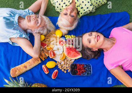 Belles femmes âgées se détendant à la maison dans le jardin - trois jolies femmes mûres reposent dans un jardin paisible de cour arrière Banque D'Images