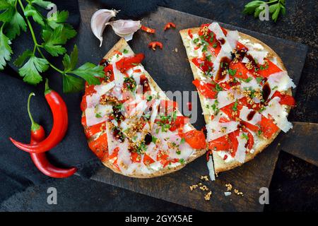 Grande bruschetta italienne avec poivrons grillés, piment, pecorino, sésame et fromage à la crème sur fond sombre Banque D'Images