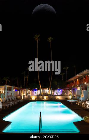 Piscine dans un hôtel avec parasols pliés et chaises de plage la nuit.Lune dans le ciel noir Banque D'Images