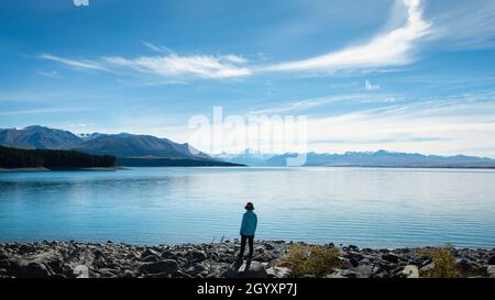 Femme debout sur les rives du lac Pukaki, bénéficiant de la vue sur le Mont Cook et les Alpes du Sud, sur l'île du Sud. Banque D'Images