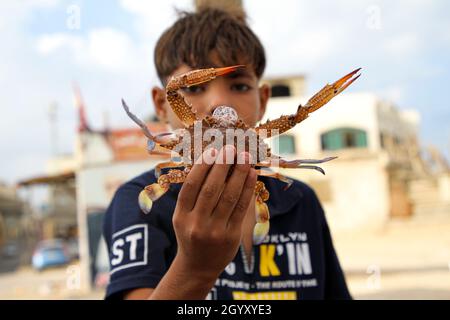 Gaza.5 octobre 2021.Un garçon présente un crabe qui vient d'être pêché au camp de réfugiés d'Al-Shati, dans la ville de Gaza, le 5 octobre 2021.Chaque jour, des milliers de Palestiniens, y compris des pêcheurs et des amateurs de pêche, se précipitent vers la mer de Gaza, jetant leurs filets dans l'eau pour attraper des crabes.TO GO WITH 'Feature: La saison de pêche au crabe offre des emplois temporaires aux Gazaouiss' Credit: Rizek Abdeljawad/Xinhua/Alamy Live News Banque D'Images