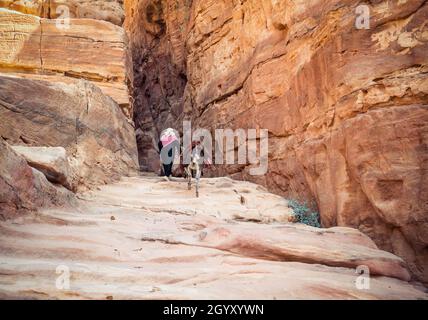 Femme arabe à bord d'un âne sur le sentier Ed-Deir (sentier du monastère) dans l'ancienne ville de Pétra, en Jordanie. Banque D'Images