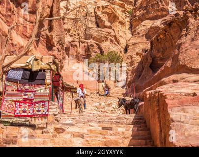 Homme arabe à cheval sur un âne sur le sentier Ed-Deir (sentier du monastère) dans l'ancienne ville de Pétra, en Jordanie. Banque D'Images