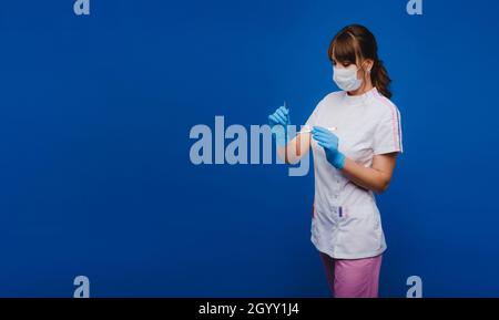 une femme médecin chirurgien tient un scalpel sur fond bleu. Banque D'Images