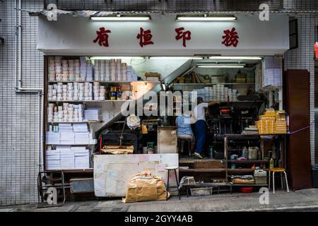 Un couple chinois exploite une entreprise d'impression depuis l'espace sous un escalier dans Wellington Street, Central, Hong Kong Island Banque D'Images