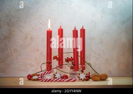 Quatre bougies rouges, une est allumée pour le premier dimanche avant Noël, décoration de l'Avent sur une table en bois contre un mur rustique, espace de copie, sélection de FO Banque D'Images