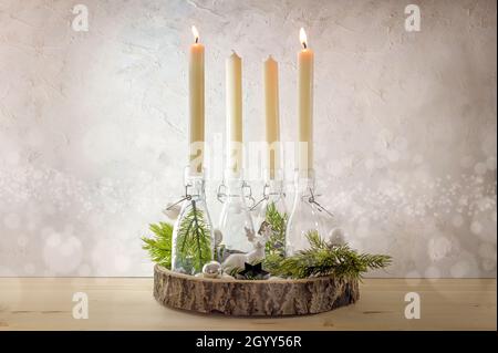 Couronne de l'Avent créatif, bougies en bouteilles sur un panneau en bois avec des branches de sapin et décoration contre un mur rustique léger, deux sont illuminés au second S. Banque D'Images