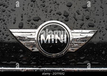 Un logo et un badge argentés pour la marque Mini sur un capot noir recouvert de gouttes de pluie d'une mini voiture à hayon, Royaume-Uni Banque D'Images