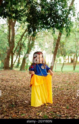 Une petite fille hispanique mignonne portant une robe blanche neige comme son costume d'Halloween dans une forêt Banque D'Images