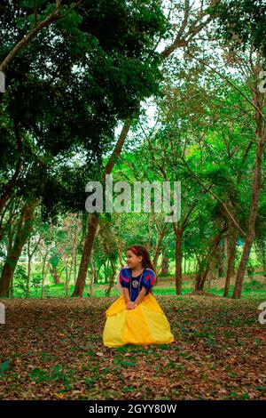 Une petite fille hispanique mignonne portant une robe blanche neige comme son costume d'Halloween dans une forêt Banque D'Images