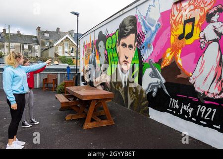 Jeunes femmes montrant une fresque de Michael Collins, figure emblématique de l'Irlande Banque D'Images