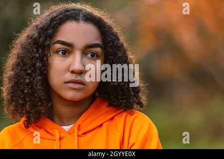 Portrait extérieur de beau triste et réfléchi déprimé mixte race biracial Africain American fille adolescente jeune femme dehors portant un orange Banque D'Images