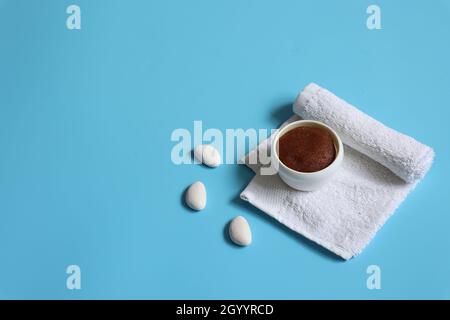 Composition balnéo minimaliste avec gommage naturel et serviette sur fond bleu, espace de copie, concept de soin du visage et du corps. Banque D'Images
