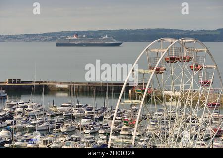 Le navire de croisière Cunard Queen Victoria a été ancré à Tor Bay, dans le sud du Devon pendant la pandémie du coronavirus, plus le port de Torquay et la grande roue. Banque D'Images