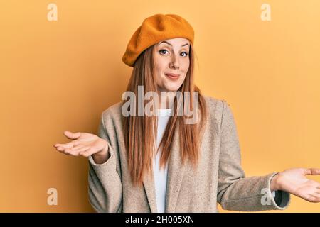 Jeune femme irlandaise portant le regard français avec beret expression sans indice et confuse avec les bras et les mains soulevées. Doute concept. Banque D'Images