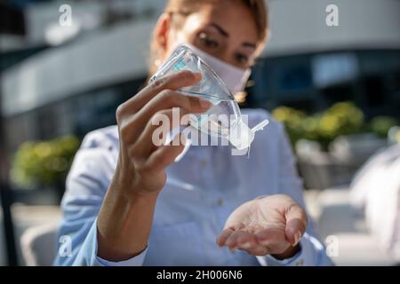 Gros plan d'une femme d'affaires avec masque facial distribuant du gel désinfectant à portée de main.Concept d'hygiène et de protection contre les virus Banque D'Images