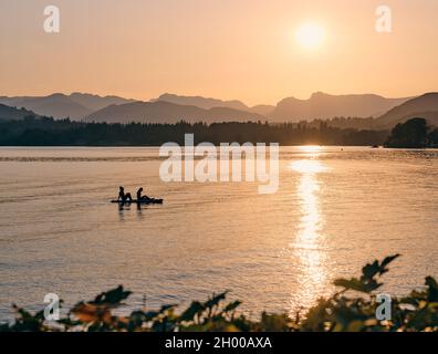 Paddelboarding / Paddleboarders appréciant le soleil couchant sur le lac Windermere et les Langdales lointaines à Low Wood Bay, Lake District Cumbria Angleterre Banque D'Images