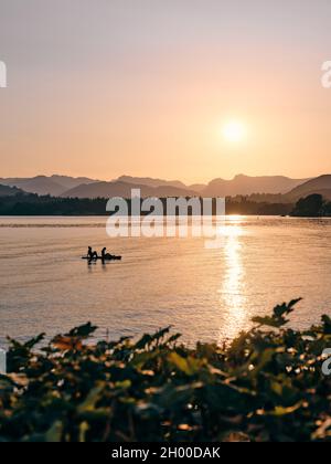 Paddelboarding / Paddleboarders appréciant le soleil couchant sur le lac Windermere et les Langdales lointaines à Low Wood Bay, Lake District Cumbria Angleterre Banque D'Images