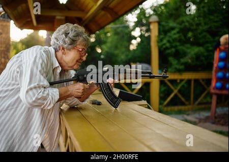 Grand-mère avec armes à feu pose dans la galerie de tir Banque D'Images