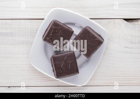 Trois chocolats doux avec une soucoupe sur une table en bois, vue rapprochée sur le dessus. Banque D'Images