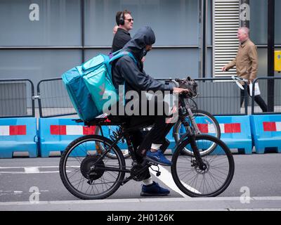 Pilote Deliveroo sur vélo électrique aux feux de circulation dans la ville de Londres Banque D'Images