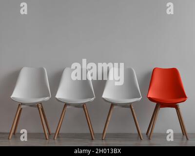 Trois chaises blanches vides et une rouge sur fond de mur gris dans le bureau ou la chambre.Intérieur minimaliste simple, personne, espace libre.Recrutement d'emplois, leade Banque D'Images