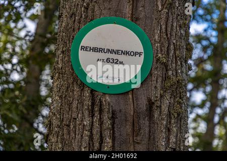 Un panneau vert et blanc du Club Vosgien Guebwiller marque le sommet du Rehbrunnenkopf à 632 mètres sur un tronc d'arbre près de Rimbach-près-Guebwiller dans les Vosges, Alsace, France. Banque D'Images