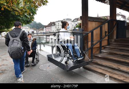 Ascenseur accessible en fauteuil roulant utilisé par une jeune femme sur le pont de la chapelle de Lucerne, en Suisse Banque D'Images