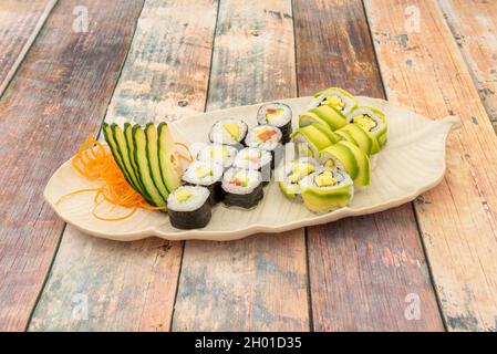 Plateau de sushi Maki de légumes avec riz blanc japonais roulé avec de l'avocat et de l'algue de Nori avec des concombres frais et de la tomate Banque D'Images