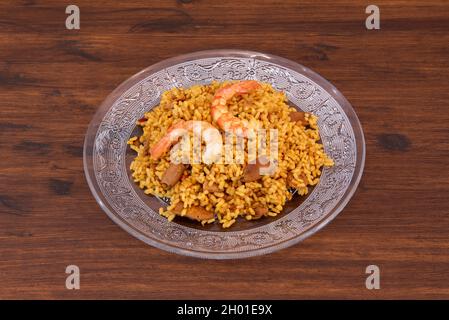 Assiette en verre avec une portion de paella de riz pastoret aux crevettes et calmars dans un restaurant de tapas espagnol Banque D'Images