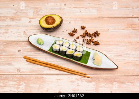 Roulé maki à l'avocat mûr servant avec du wasabi, du riz blanc et de l'algue nori avec des baguettes, de l'anis étoilé et du ginseng Banque D'Images